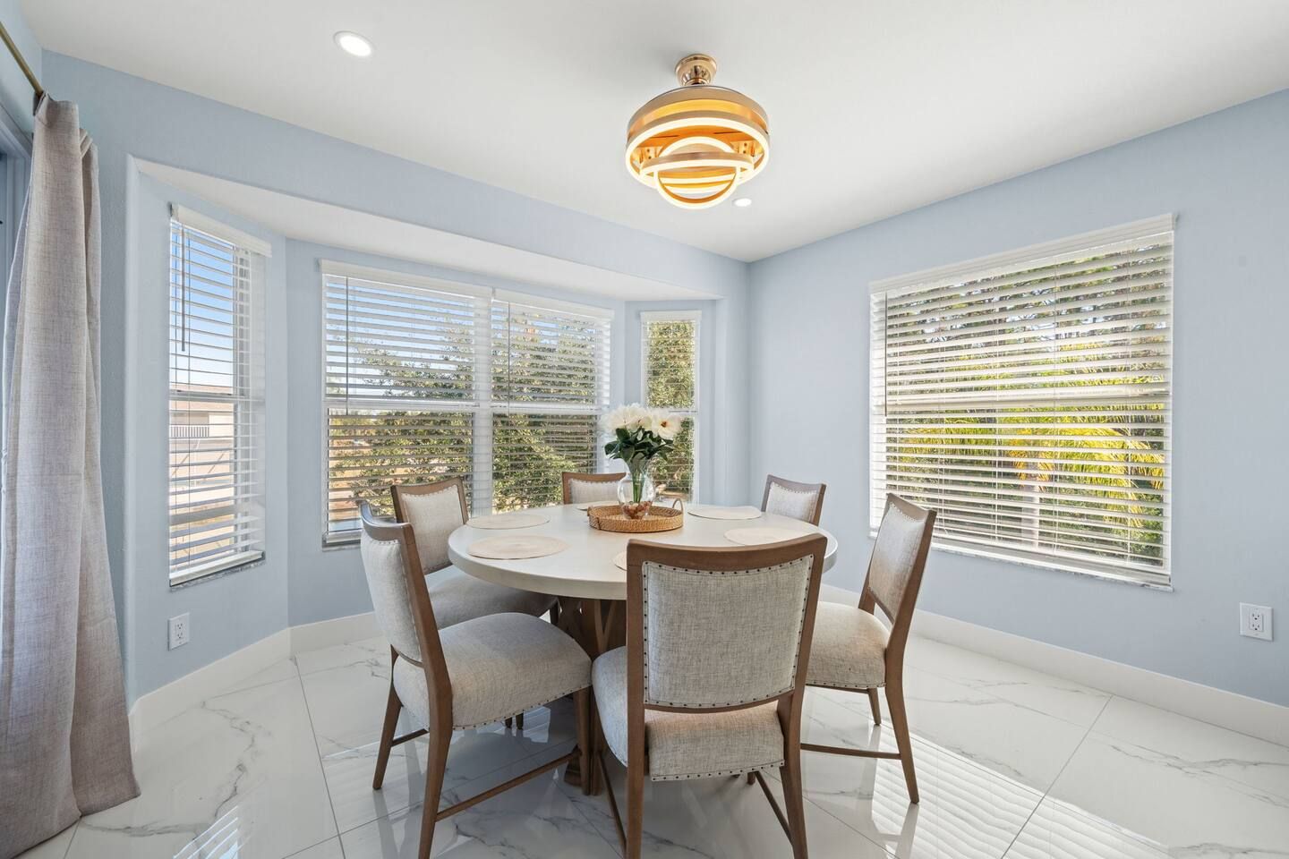 A dining area with a round table, chairs, and a ceiling light fixture.