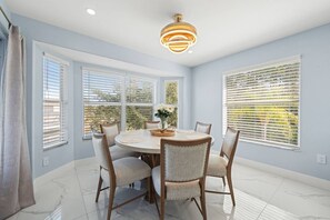 A dining area with a round table, chairs, and a ceiling light fixture.