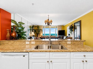 A kitchen with a granite countertop, white cabinets, a stainless steel sink, and a dishwasher. - Emerald Beach 736 | Gulf-Front | Sleeps 8 (Panama City Beach)