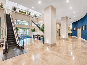 A spacious lobby with a central escalator, a blue accent wall, and a polished marble floor. - Emerald Beach 736 | Gulf-Front | Sleeps 8 (Panama City Beach)