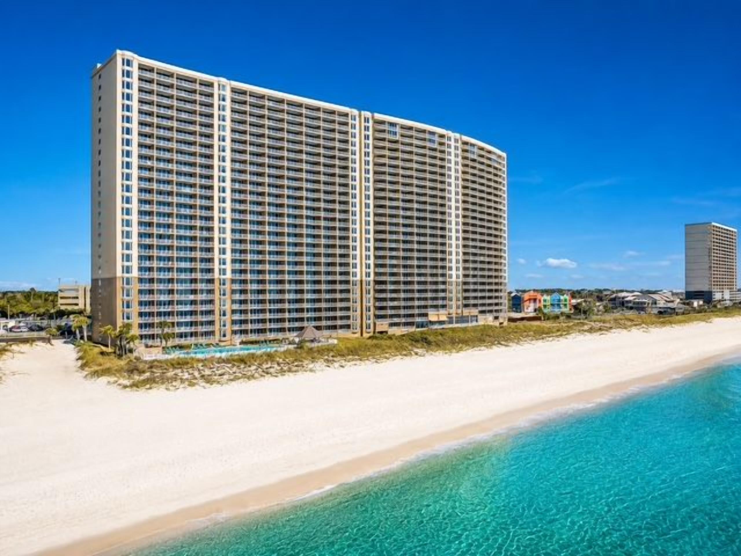 Ein großes Hotel mit mehreren Etagen, einer Strandlage und einem strahlend blauen Himmel.