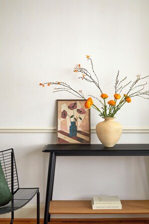 Una mesa con un florero y una obra de arte enmarcada.