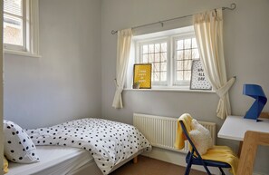 A bedroom with a bed, a chair, a radiator, and a window with curtains. - Elegant home in the heart of Wimbledon (London)
