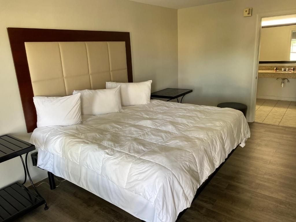 A hotel room with a large bed, a bedside table, and a small table.