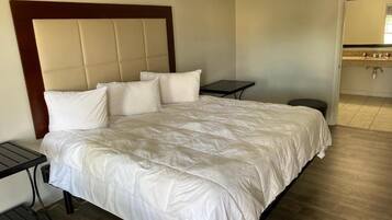 A hotel room with a large bed, a bedside table, and a small table.