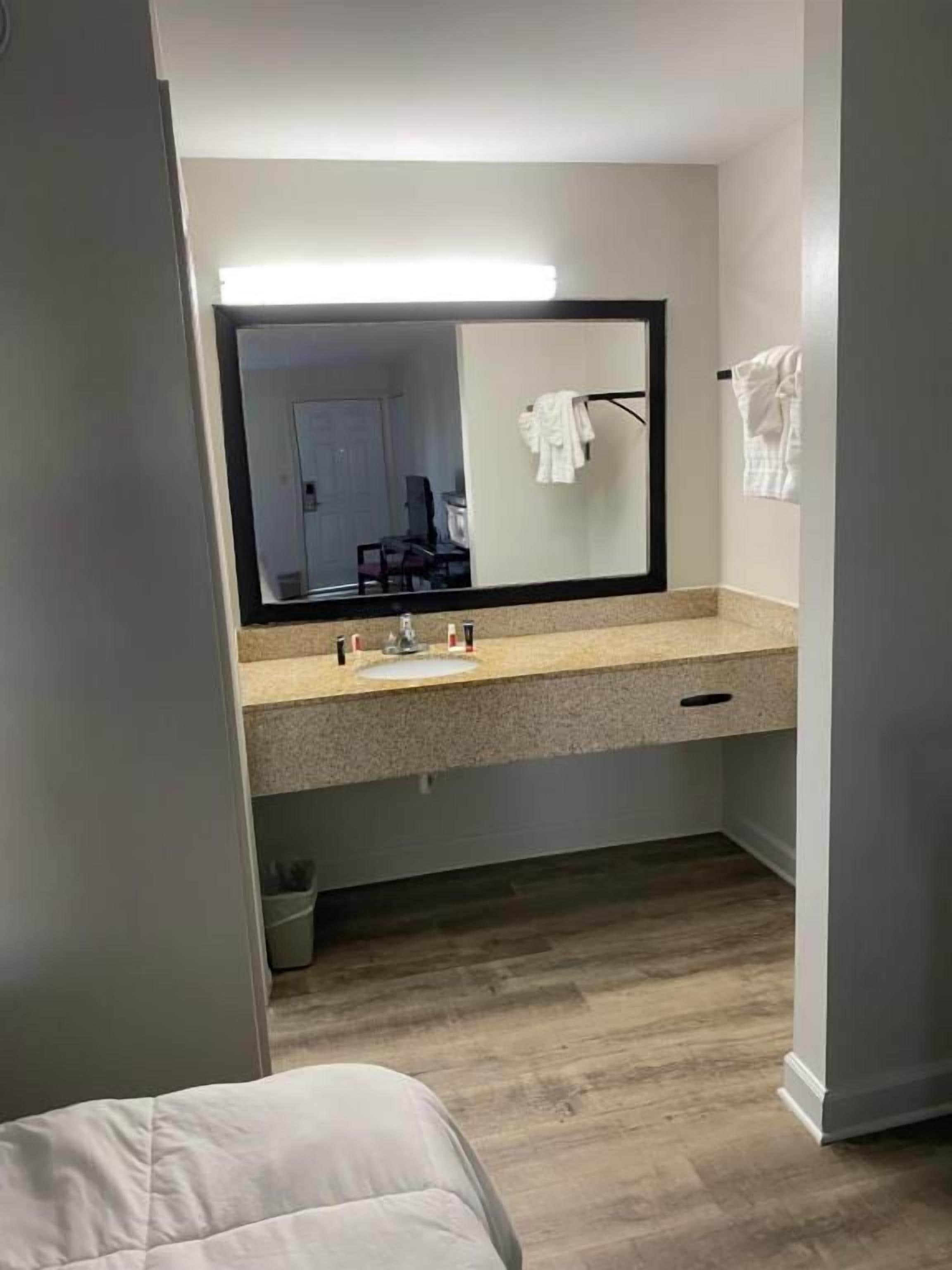 A bathroom with a mirror, sink, and towel rack.