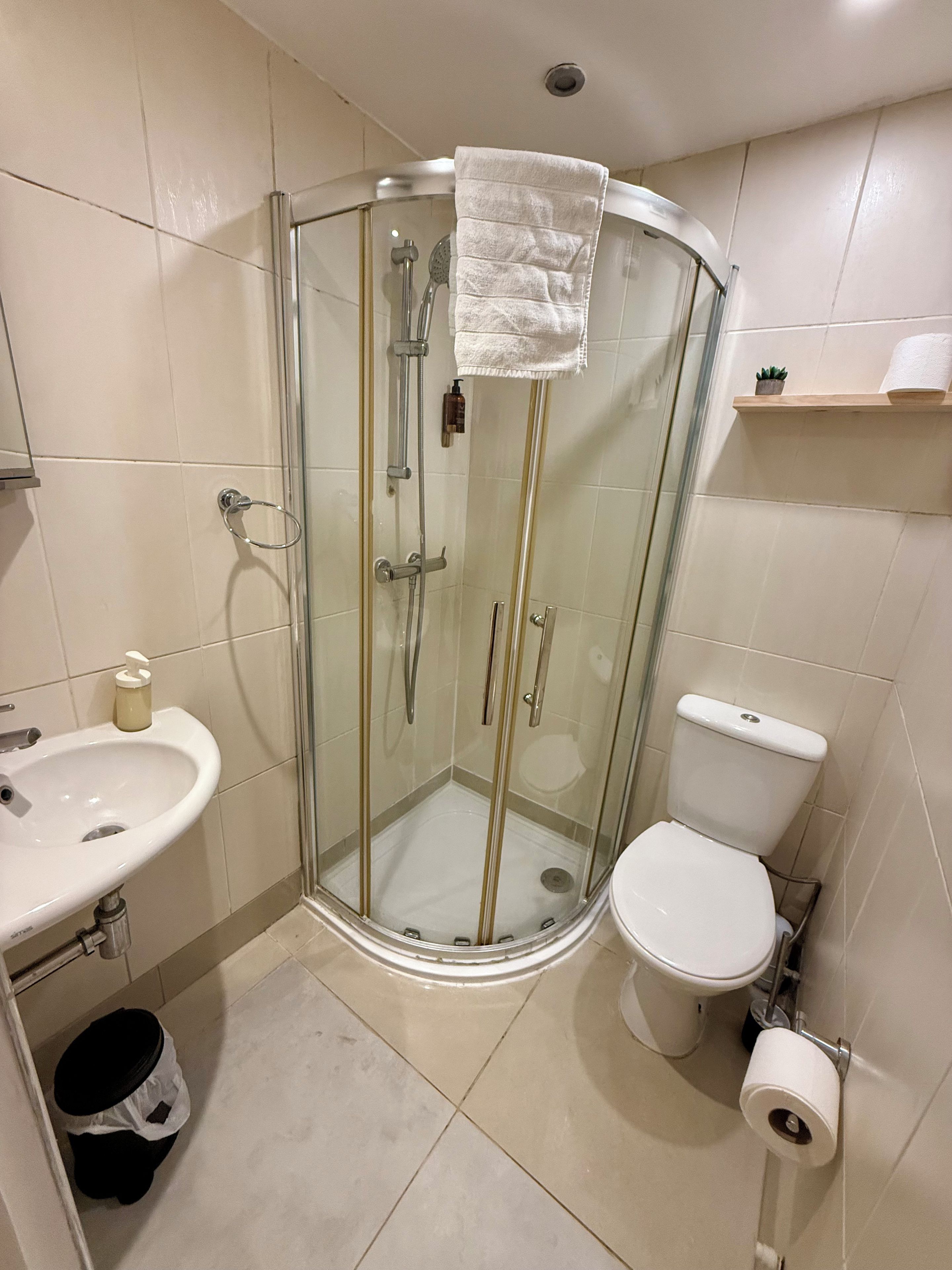 Een moderne badkamer met een douchecabine van glas, een wit wastafelmeubel en een toilet.
