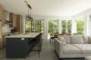 A modern kitchen with a central island, bar stools, and a dining area with a table and chairs.