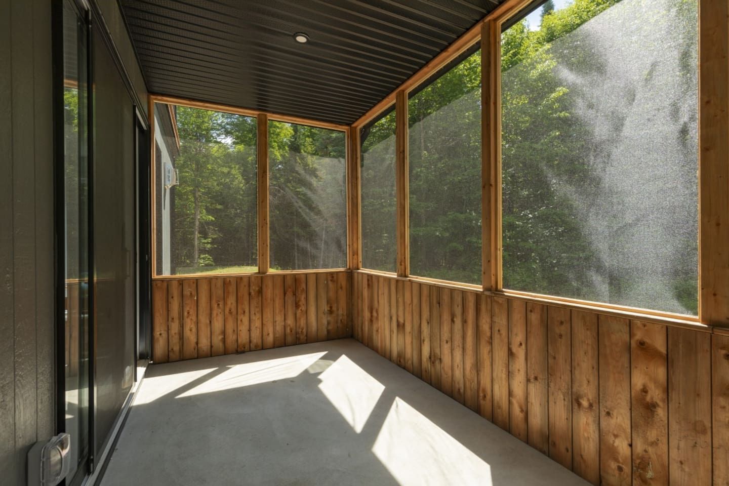Una habitación con amplios ventanales, paredes de madera y techo inclinado.