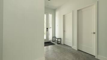 A hallway with a grey carpet, white walls, and a door at the end.