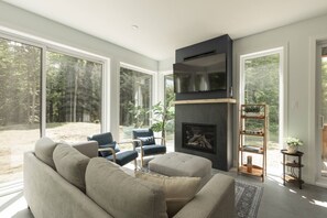 A modern living room with a fireplace, large windows, and a sofa.