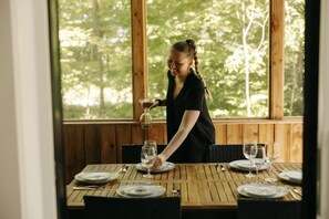 A dining area with a table set for four, surrounded by wooden walls and large windows.