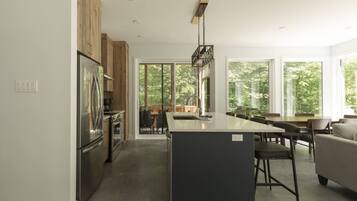 A modern kitchen with a central island, wooden cabinets, and a dining area with a sofa.