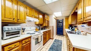 Una cocina con armarios de madera, una estufa blanca y una puerta azul.