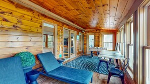 A wooden cabin interior with a sofa, a table, and a patterned rug.