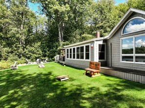 Ett hus med en täckt uteplats, en gräsmatta och utomhusmöbler.
