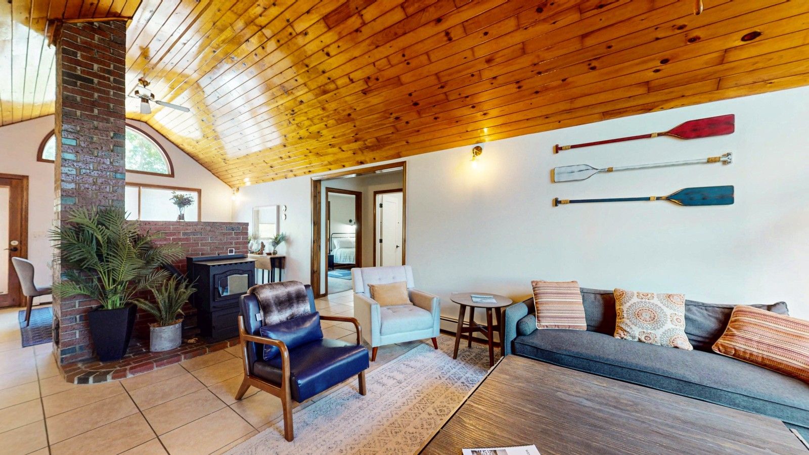 A cozy living room with a fireplace, seating area, and wooden ceiling.