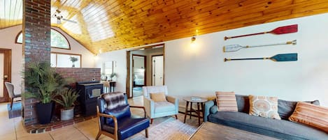 A cozy living room with a fireplace, seating area, and wooden ceiling.