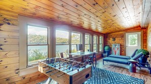 Ett rum med ett fotbollsspel, ett skrivbord med en dator och en soffa.