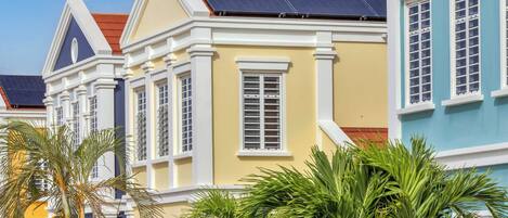 A row of colorful colonial-style buildings with large windows and solar panels on the roofs.