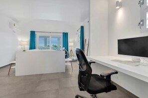 Ein moderner Büroarbeitsplatz mit Schreibtisch, Stuhl, Computer und Blick ins Freie durch ein Fenster.