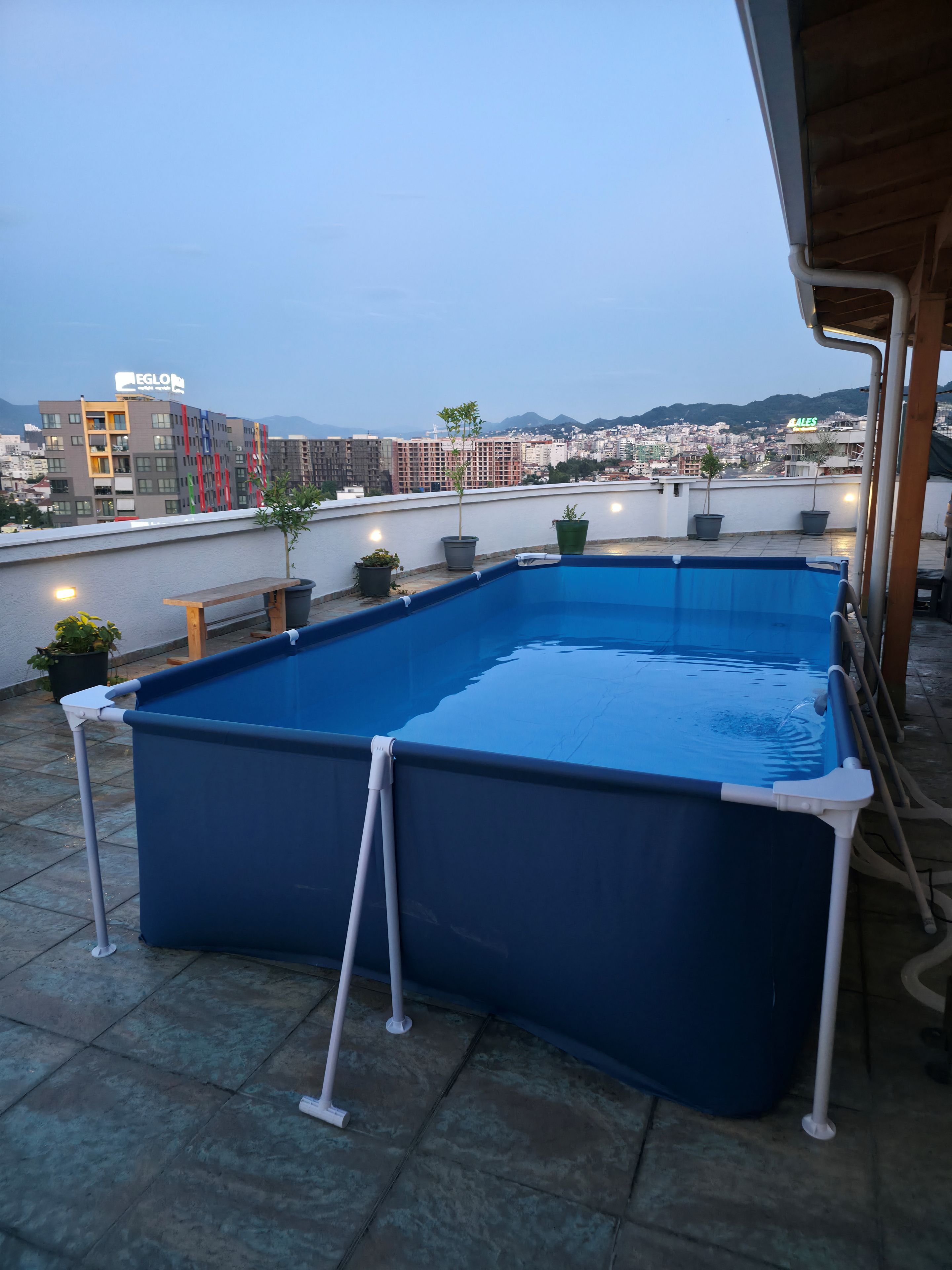 Ein Dachpool mit Blick auf eine Stadtlandschaft und Berge im Hintergrund.