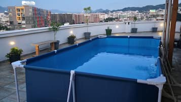 Ein Dachpool mit Blick auf eine Stadtlandschaft und Berge im Hintergrund.