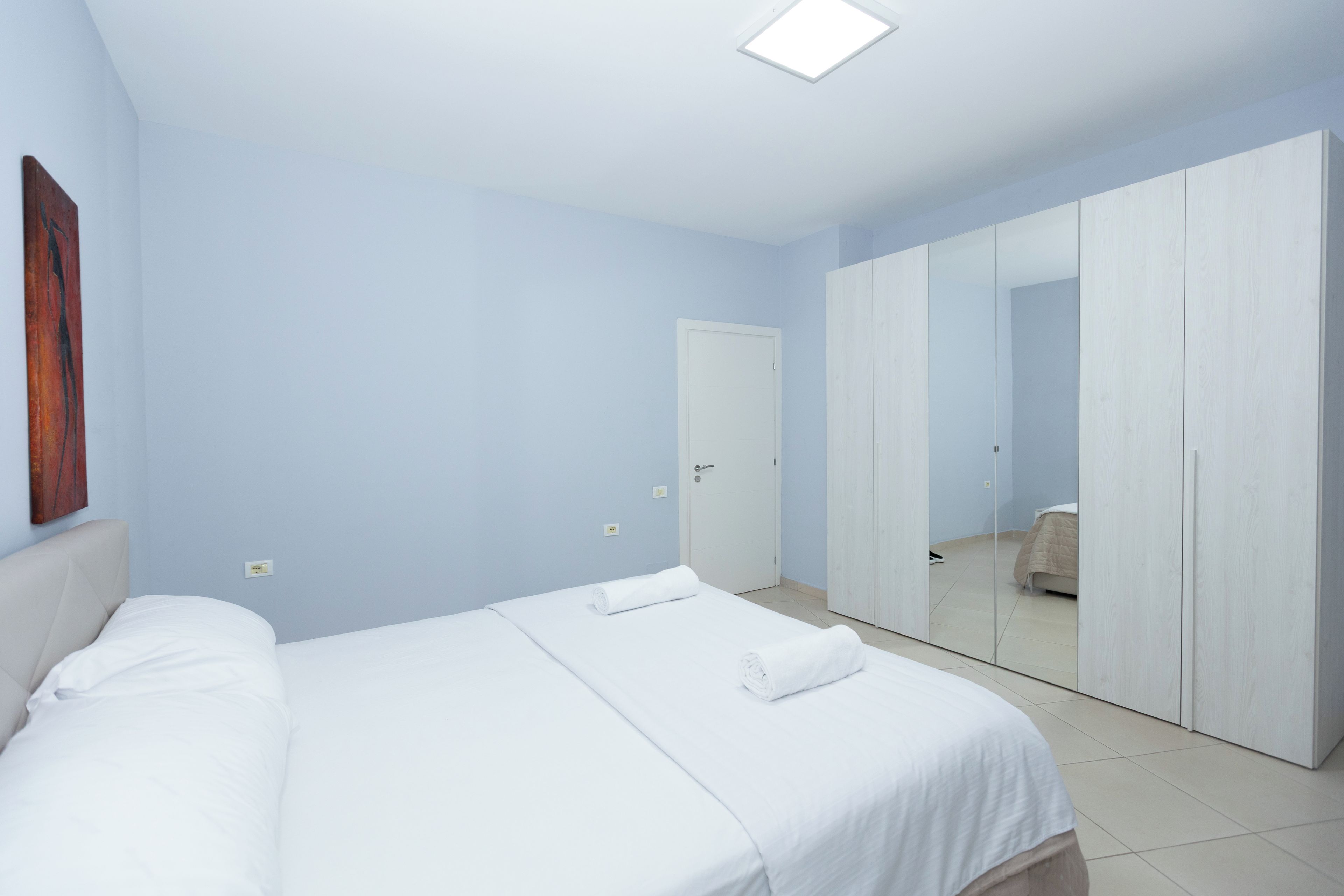 Ein Schlafzimmer mit einem Bett, einem Kleiderschrank und einem Spiegel.