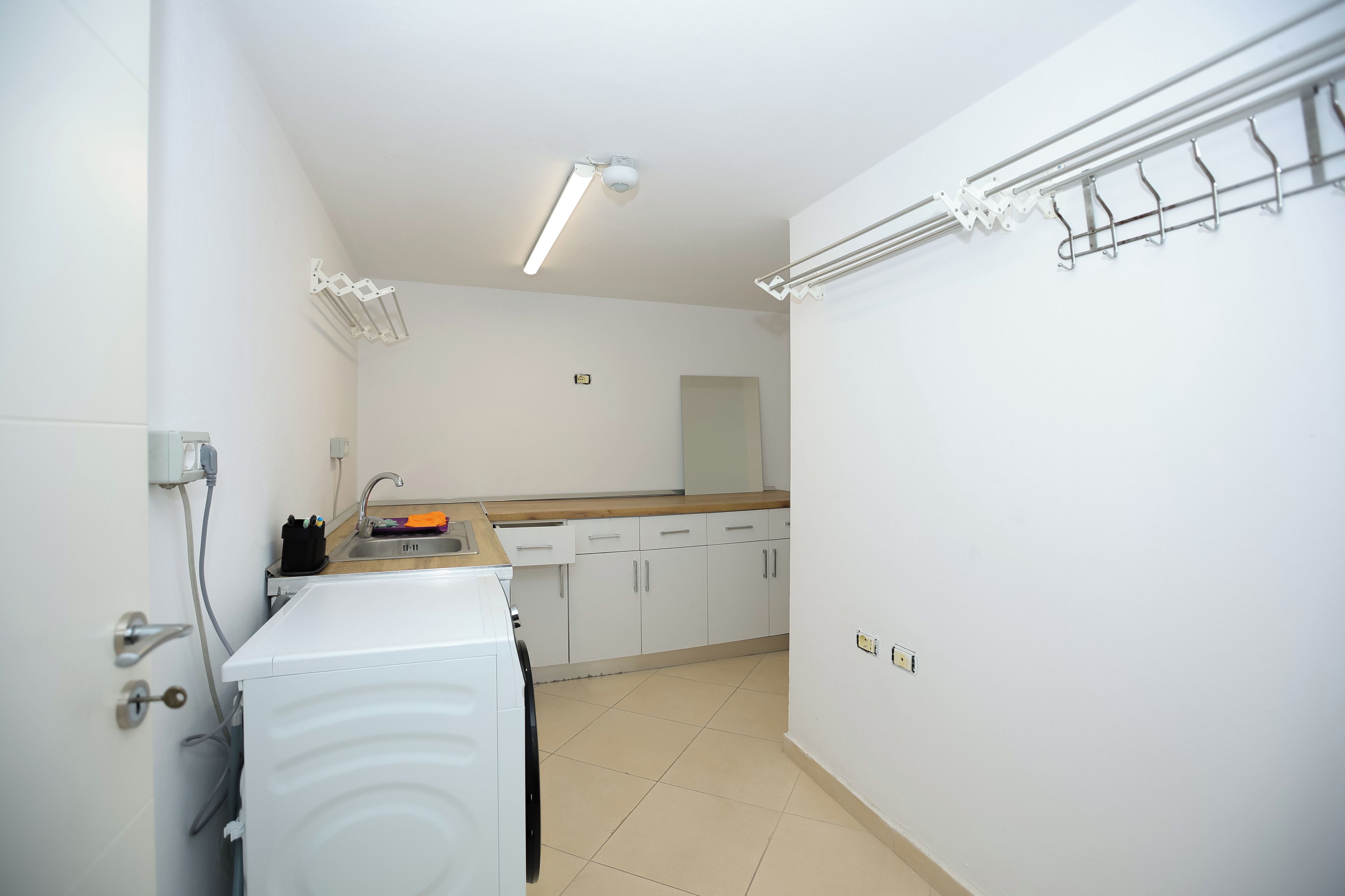 Une cuisine compacte équipée d’un lave-linge, d’un évier et d’un plan de travail.