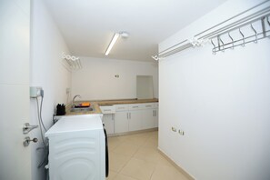 A compact kitchen with a washing machine, a sink, and a countertop. - Private Rooftop: Hot Tub, Pool & Views • 2BR (Kashar)