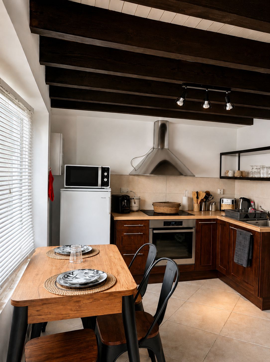 A kitchen with a wooden table, chairs, a microwave, a stove, and a range hood.