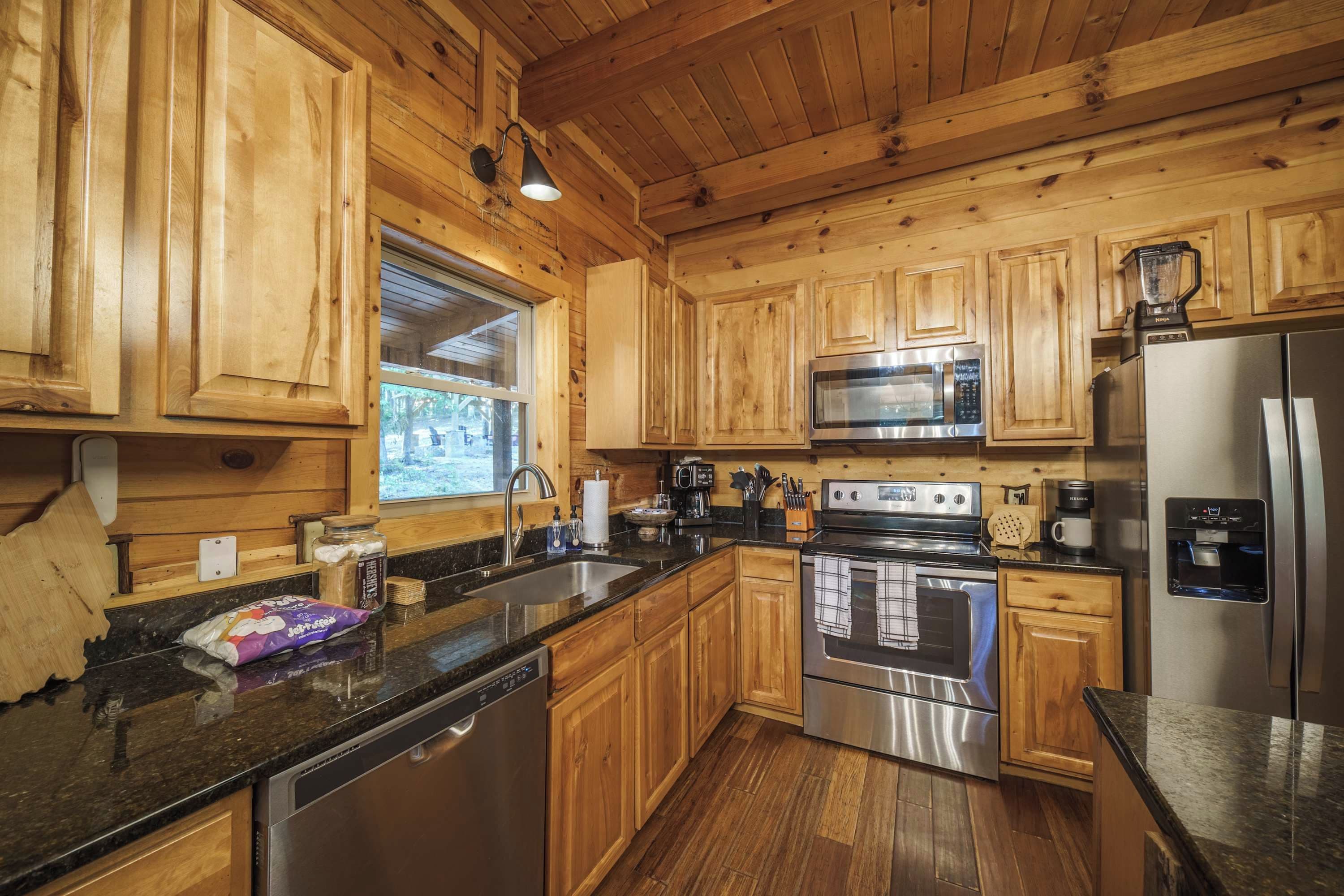 A kitchen with wooden cabinets, stainless steel appliances, a dishwasher, and a window.