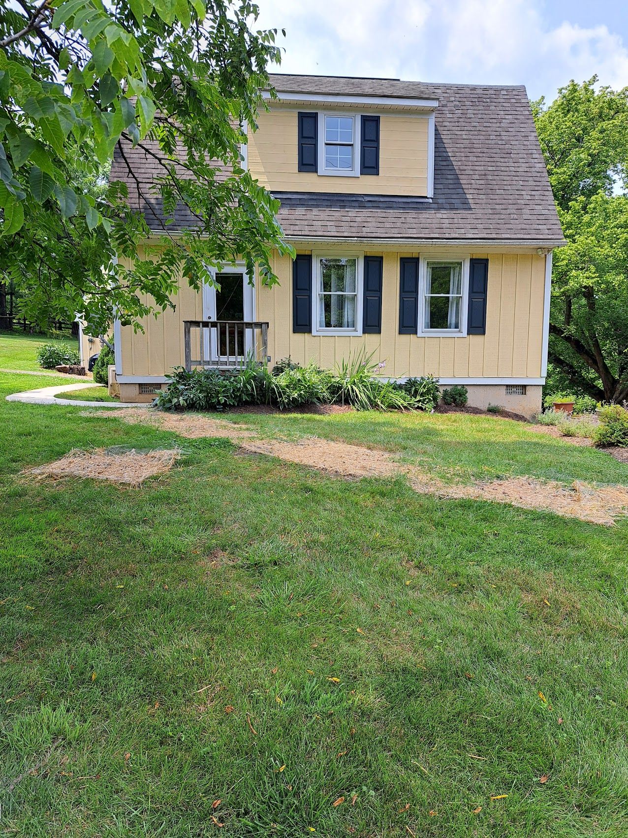 A two-story house with a front porch and a well-maintained lawn.