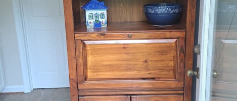 Un gabinete de madera con repisas, un tazón azul y un recipiente con forma de casa.