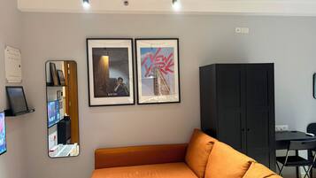 A modern living room with a sofa, framed pictures, a cabinet, and a desk.