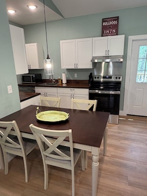 A kitchen with white cabinets, a stainless steel stove, and a dining table with chairs.