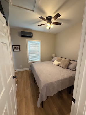 A bedroom with a bed, a ceiling fan, a window with blinds, and a picture on the wall. - Secluded Two-Bedroom House with Bunk Nook 5 minutes from Campus. (Starkville)