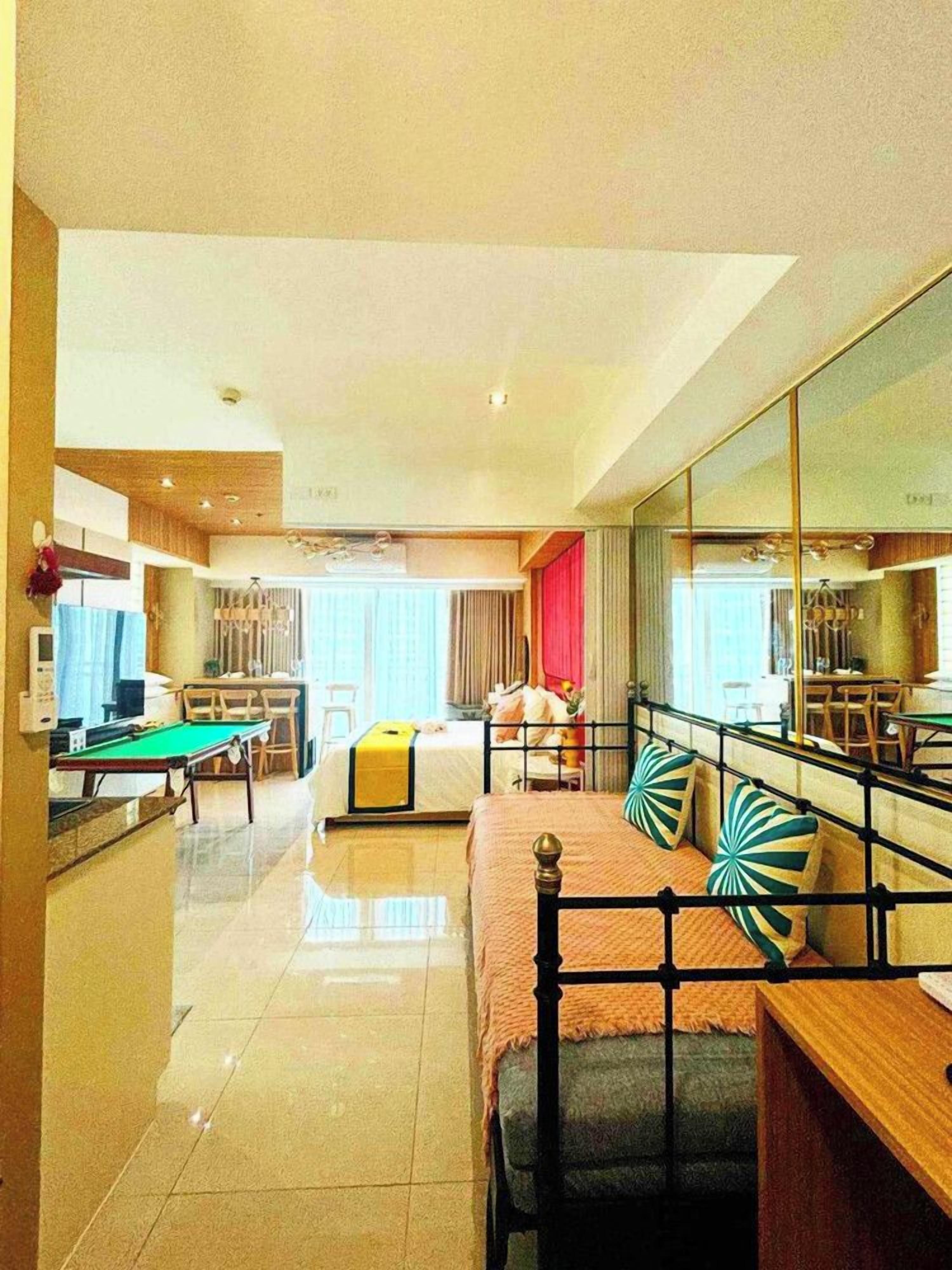 A hotel room with a bed, a desk, a dining table, and a pool table.