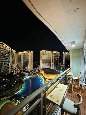 A balcony with a view of high-rise buildings and a swimming pool. - Studio Premium Suite (Paranaque)