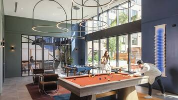 A pool table in a modern indoor space with large windows and a view of the outdoors.