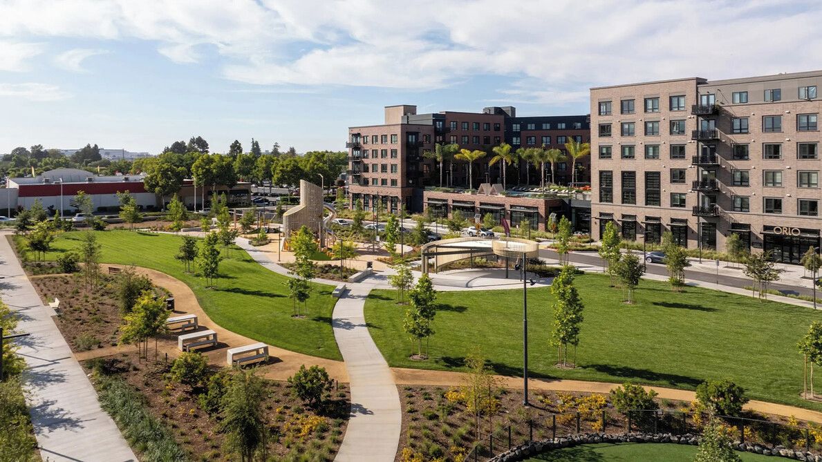 A modern building complex with multiple floors, a central courtyard with pathways, and surrounding greenery.