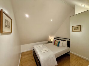 Une chambre à coucher avec un lit, une table de chevet, une lampe et deux tableaux encadrés accrochés aux murs.