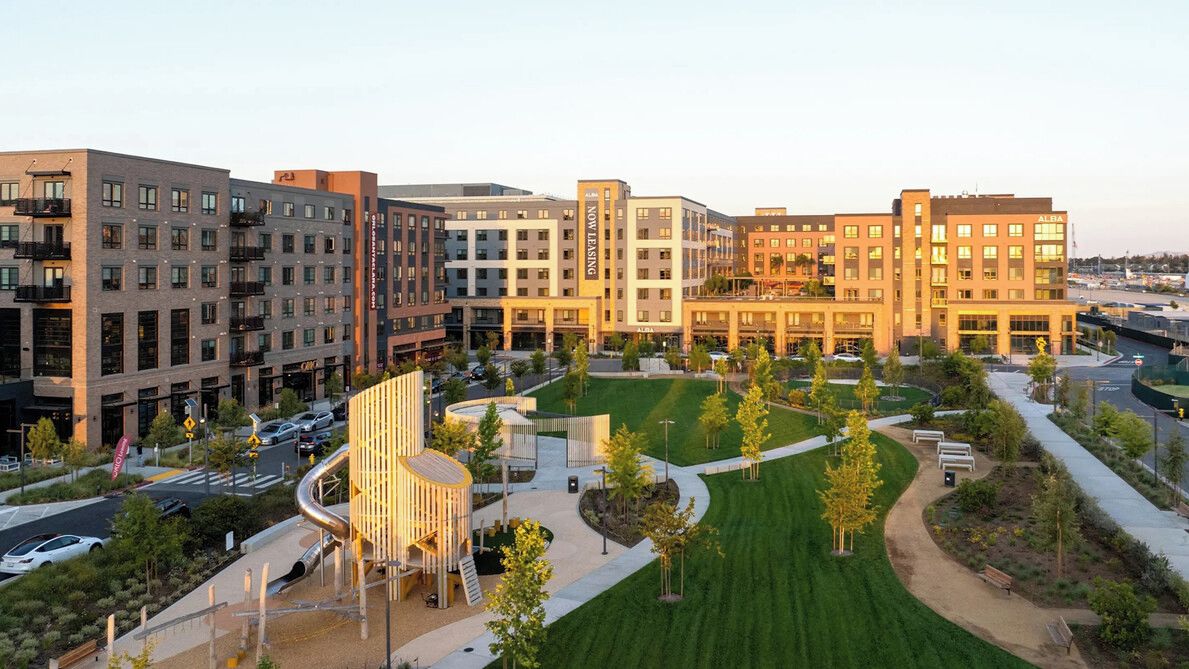 A modern hotel complex with multiple buildings, a central courtyard with greenery, and a parking area.