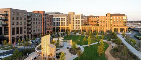 A modern hotel complex with multiple buildings, a central courtyard with greenery, and a parking area.