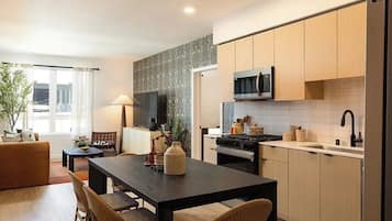 A modern kitchen with a dining area, wooden cabinets, a microwave, and a large window.