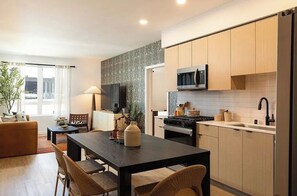 A modern kitchen with a dining area, wooden cabinets, a microwave, and a large window. - Modern 1BR at Alba in Santa Clara with Pool (Santa Clara)