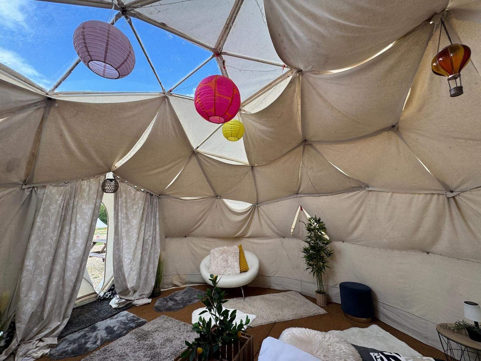 Eine Zeltoase mit Blick auf den Himmel, einer gepolsterten Sitzecke und einem kleinen Tisch mit einer Lampe.
