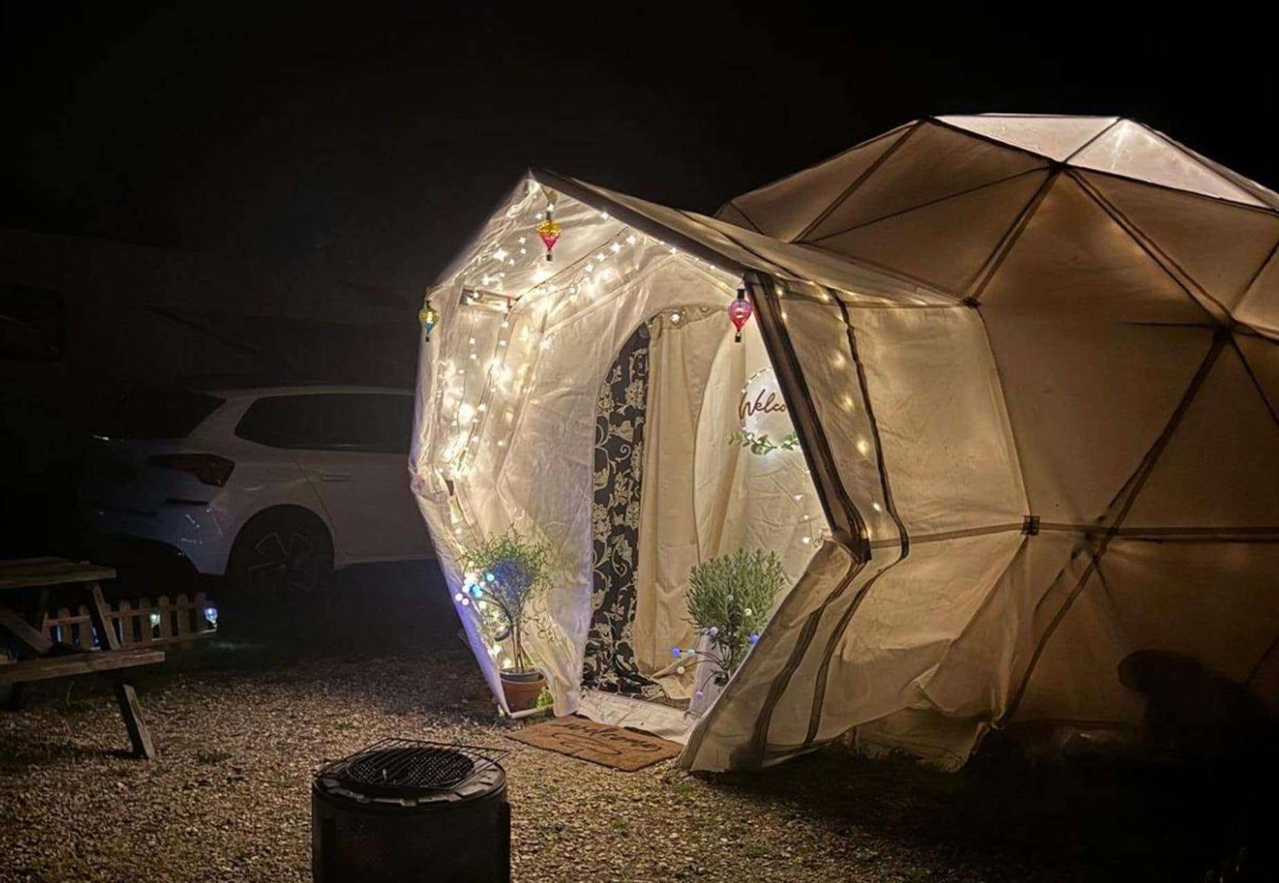 Une tente avec une porte, des guirlandes lumineuses et un panneau d’accueil.