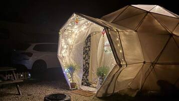 Une tente avec une porte, des guirlandes lumineuses et un panneau d’accueil.