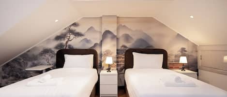 A twin room with two beds, a nightstand with a lamp, and a large mural of mountains on the wall.